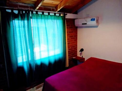 a bedroom with a window with a blue curtain at Cabaña Ángeles del Bosque 5 in Villa Ciudad Parque