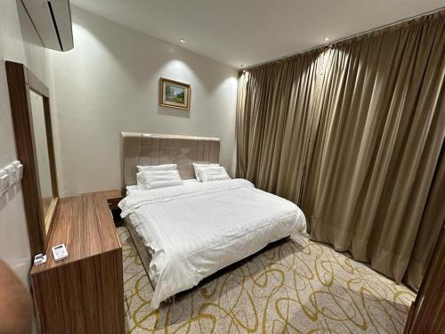 una camera da letto con un grande letto con lenzuola bianche di فندق نجران ول ان a Najran