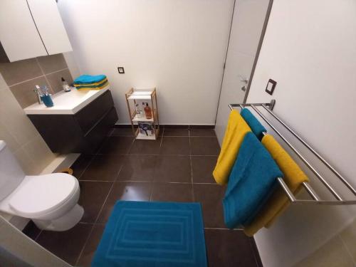 La salle de bains est pourvue de toilettes ainsi que de serviettes bleues et jaunes. dans l'établissement Les pieds dans l'eau chez Syl, à Le Moule