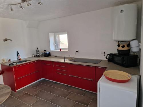 uma cozinha com armários vermelhos e um frigorífico branco em Entre lac et montagne em Cluses