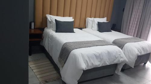two beds in a hotel room with white sheets and pillows at Honolulu Lifestyle Guest Lodge in Burgersfort