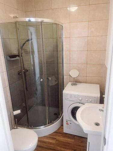 a bathroom with a shower and a washing machine at 2 bed London Studio Flat, Fully Equipped. in Croydon