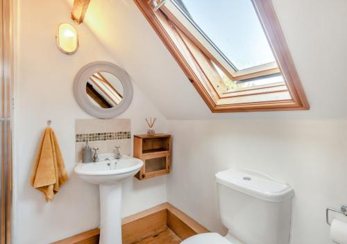 łazienka z białą toaletą i świetlikiem w obiekcie 1 Cutty Sark Cottages w mieście West Runton