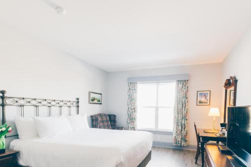 um quarto com uma grande cama branca e uma televisão em The Loyalist Country Inn & Conference Centre em Summerside