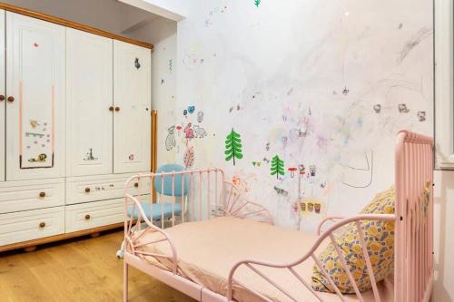 um berçário com um berço rosa num quarto com uma parede coberta de autocolantes em 4 Bedroom Spacious Apartment in Nisantasi em Istambul