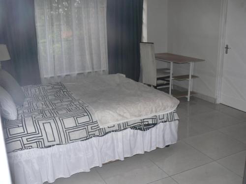1 dormitorio con cama, escritorio y mesa en Ilanga Libalele en Johannesburgo