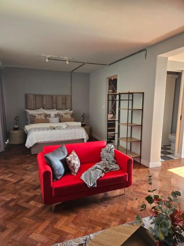 uma sala de estar com um sofá vermelho em frente a uma cama em @Derricks Luxury Apartments 2 em Joanesburgo