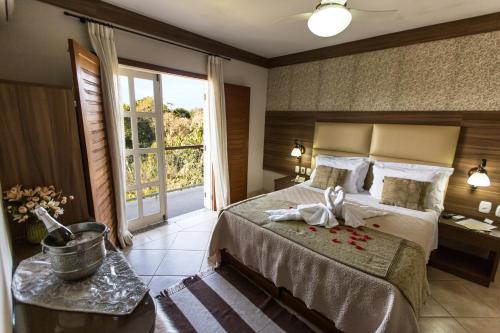 a bedroom with a bed and a large window at Pousada Lusitânia in Pedra Azul