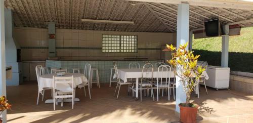 a patio with white tables and chairs and a television at Pousada Oásis 2 in Fama