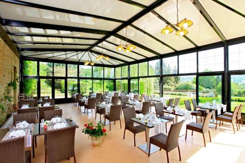 une salle à manger avec tables, chaises et fenêtres dans l'établissement Hotel Restaurant La Verperie, à Sarlat-la-Canéda