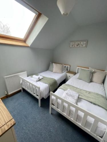 two twin beds in a room with a window at AIRDSIDE COTTAGE in Castle Douglas