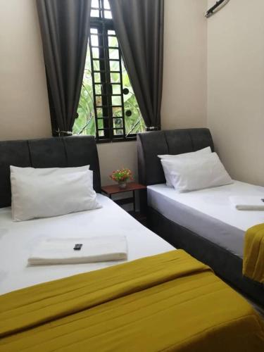 dwa łóżka siedzące obok siebie w pokoju w obiekcie Number Ten Guest House w mieście Ayer Keroh