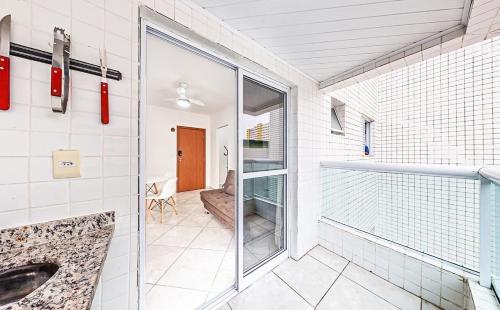 a bathroom with a sink and a glass door at Bom apto na Ocian Praia Grande - ZN01H in Praia Grande