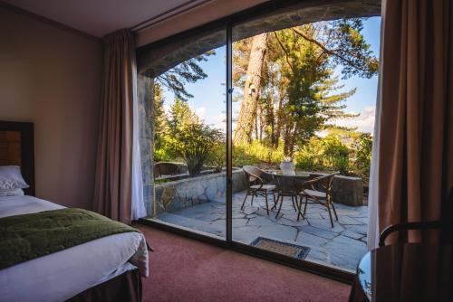 a bedroom with a view of a patio with a table and chairs at Hotel Puerta del Sur in Valdivia