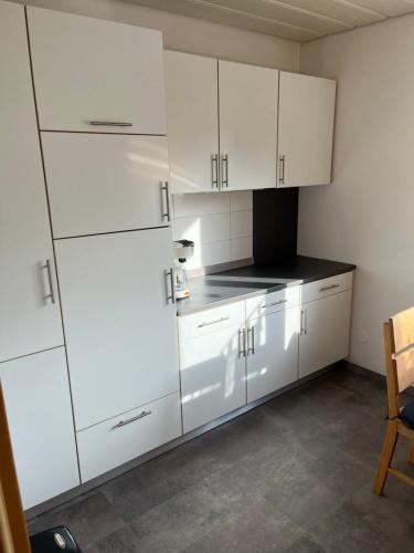 a kitchen with white cabinets and a black counter top at Ferienwohnung in ruhiger Lage in Thurnau