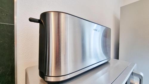 un four micro-ondes en argent assis au-dessus d'un comptoir dans l'établissement Chez JM - Calme - Chic - Fibre - Relax BNB, à Mulhouse