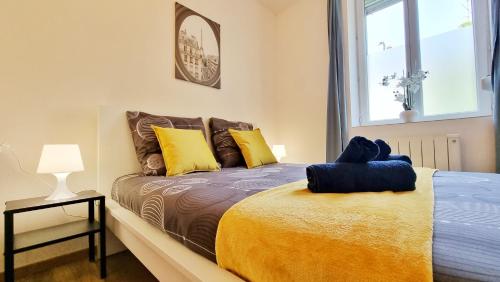 a bedroom with a bed with yellow and blue pillows at Chez JM - Calme - Chic - Fibre - Relax BNB in Mulhouse