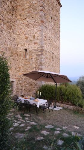 une table et des chaises sous un parasol devant un bâtiment dans l'établissement Medieval Tower in Umbria with Swimming Pool, à Monte lʼAgello