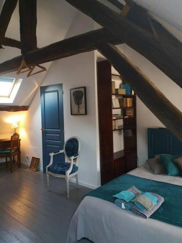 une chambre avec un lit et une chaise dans une pièce dans l'établissement Au cœur de Mortagne, un balcon sur le Perche, à Mortagne-au-Perche
