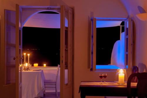 a dining room with a table and a window with a candle at Thirea Suites in Oia