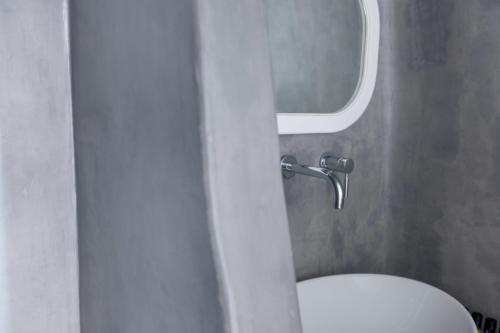 a bathroom with a white toilet and a mirror at Thirea Suites in Oia