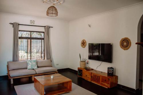 uma sala de estar com um sofá e uma televisão em Tropicana House em Arusha