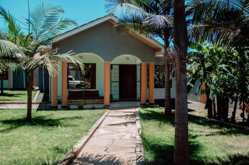 une maison avec des palmiers devant elle dans l'établissement Tropicana House, à Arusha