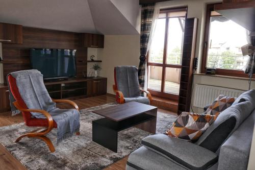 a living room with two chairs and a tv at GreenView Apartment in Rzeszów