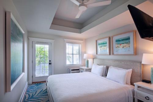 a bedroom with a white bed and two windows at Coco Plum Inn in Key West