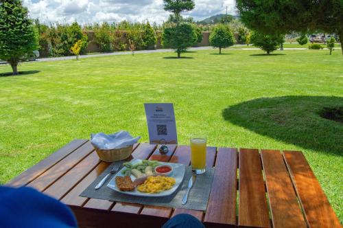 uma mesa de piquenique com um prato de comida e um copo de sumo de laranja em Hacienda Grande Hotel em Quetzaltenango