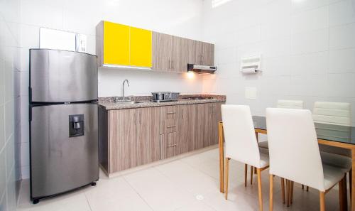 uma cozinha com um frigorífico de aço inoxidável e uma mesa em Sachar Lodging Apartahotel em Bucaramanga