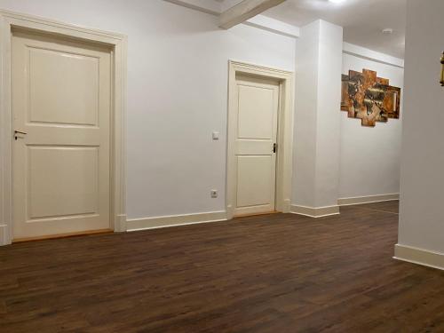 ein leeres Zimmer mit zwei weißen Türen und Holzböden in der Unterkunft Stadthaus Room 2 mit Hochbett for 3 Persons or Eltern mit 2 Kindern in Mannheim