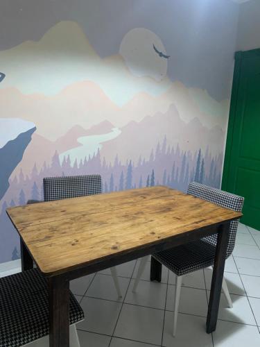 a wooden table with two chairs in front of a mountain mural at Joshua Tree Hostel - Curitiba in Curitiba