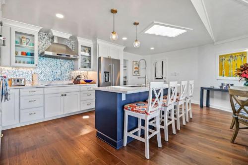 a kitchen with white cabinets and a blue island with chairs at Leisure Beach Ocean Retreat in Lower Bogue