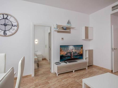 a living room with a flat screen tv and a clock at Apartamento a 50m de la playa in Platja  d'Aro