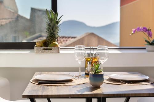 a table with plates and glasses on a table in front of a window at Sweet Calanque - Host Provence in Cassis