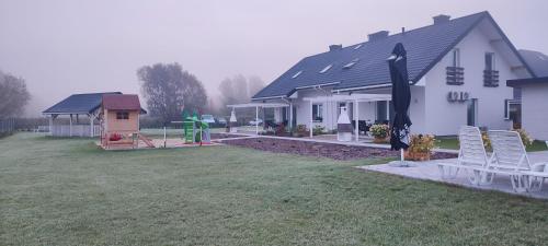 a house with a yard with chairs and a playground at Apartamenty Wilga in Wilga