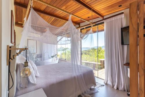 a bedroom with a bed and a large window at Gringos Boutique Hotel in Búzios