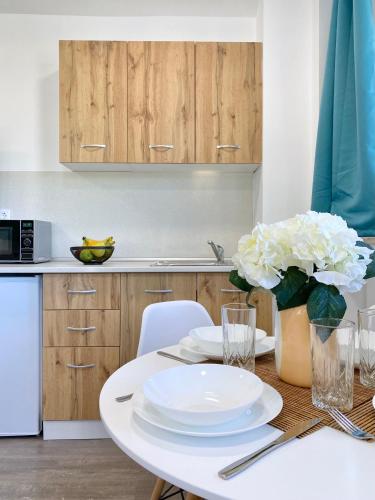 a kitchen with a table with plates and flowers on it at Hello Studios Budget Stays Free Parking & Wifi in Stara Zagora