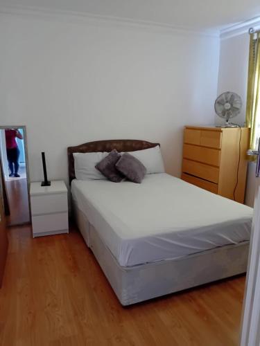 a bedroom with a white bed and a wooden floor at 2 Bed Mill Hill Flat in Mill Hill