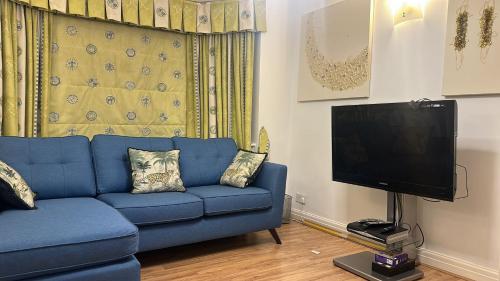 a living room with a blue couch and a flat screen tv at 2 Bed Mill Hill Flat in Mill Hill