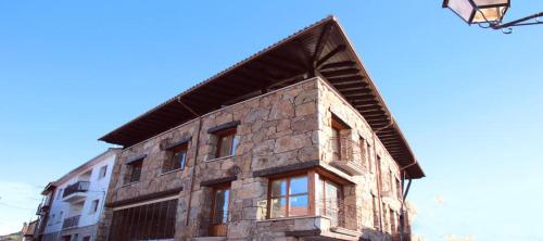 an old stone building with windows and a street light at Hotel Rural Quercus Tierra in Garganta de los Montes