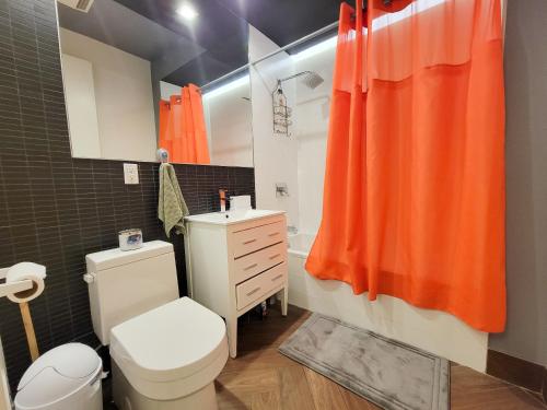 an orange shower curtain in a bathroom with a toilet at Homestyle Haven by the Water in Brooklyn