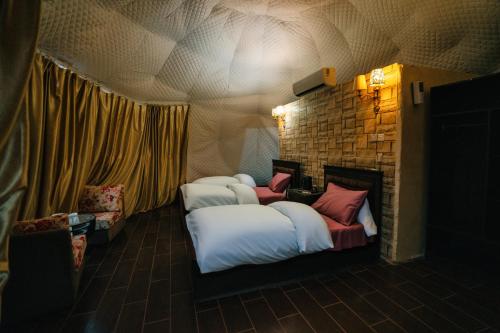 a room with three beds and a stone wall at Wadi Rum Desert Dunes Luxury Camp in Wadi Rum
