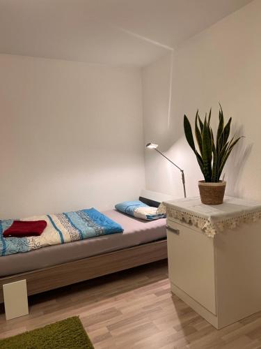 Gäste-, Handwerkerzimmer في Rosenfeld: غرفة نوم مع سرير وزرع الفخار