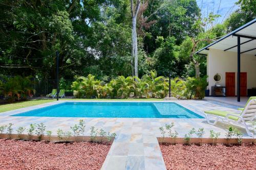 a swimming pool in a yard with two chairs and a house at LaLola Villa Privada in Cahuita
