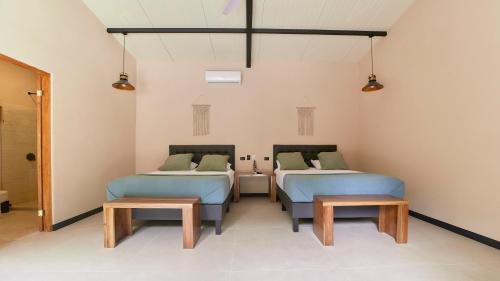 a room with two beds and two benches in it at LaLola Villa Privada in Cahuita