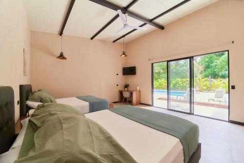 two beds in a room with a large window at LaLola Villa Privada in Cahuita