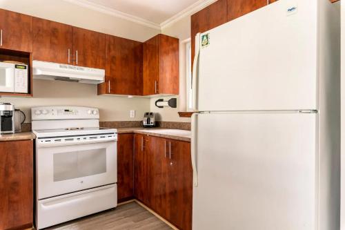 a kitchen with a white refrigerator and wooden cabinets at Aiglon by Rendez-Vous Mont-Tremblant in Mont-Tremblant