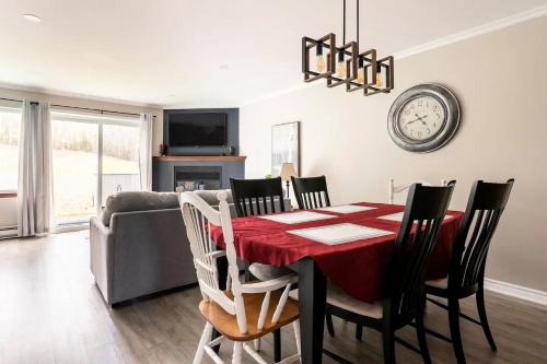 a dining room with a table and chairs and a clock at Aiglon by Rendez-Vous Mont-Tremblant in Mont-Tremblant